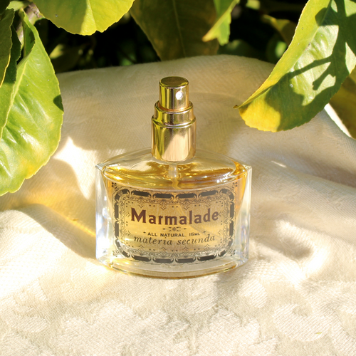 A bottle of perfume beside a citrus tree