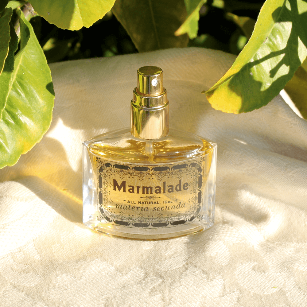 A bottle of perfume beside a citrus tree